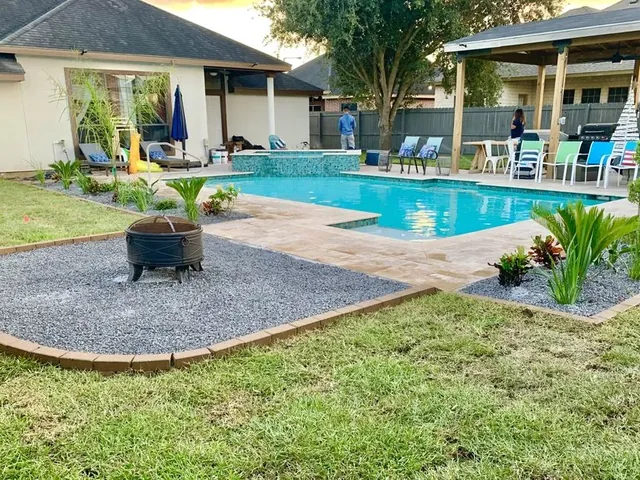 A back yard with a swimming pool, a travertine deck and a timber-posted shade structure over the patio furniture